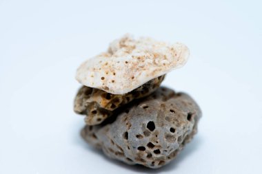 Beyaz zemin üzerine yerleştirilmiş pürüzsüz, renkli çakıl taşlarının yakın çekim makrosu doğal dokularını ve karmaşık ayrıntılarını gözler önüne seriyor..