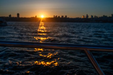 İstanbul Boğazı 'nın üzerinde çarpıcı bir günbatımı var. Gökyüzü turuncu ve pembe sıcacık renklerle parlıyor. Suyun ve şehrin üzerine güzel bir parıltı saçıyor..
