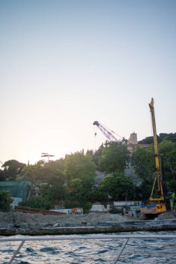 İstanbul Boğazı 'ndaki bir inşaat sahasının dinamik görüntüsü, vinçler, iskeleler ve ikonik su yoluna karşı kentsel kalkınmanın hareketli faaliyetleri.