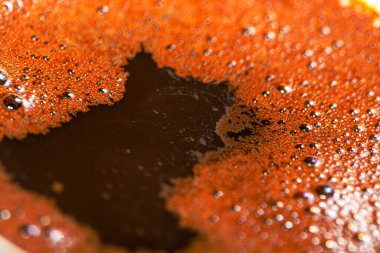 Türk kahve köpüğünün zengin, köpüklü dokusunu ve karmaşık ayrıntılarını yakalayan makro bir fotoğraf, geleneksel ve aromatik özelliklerini vurguluyor.