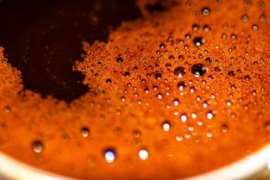 Türk kahve köpüğünün zengin, köpüklü dokusunu ve karmaşık ayrıntılarını yakalayan makro bir fotoğraf, geleneksel ve aromatik özelliklerini vurguluyor.