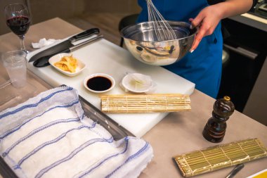 A cook preparing a meal in a sushi workshop, actively engaged in the sushi-making process with fresh ingredients and specialized tools, showcasing culinary skills. clipart