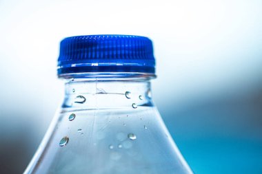 Parlayan su damlacıklarıyla kaplı plastik bir şişenin yakın çekim makrosu, dokuyu ve yoğunlaşma etkilerini vurguluyor..