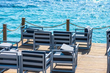 Güneşli gökyüzünün altında deniz kenarında rahat koltuklar ve koltuklar rahatlamak ve nefes kesici okyanus manzaralarının tadını çıkarmak için mükemmel bir yer sunuyor..