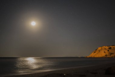 Samanyolu 'nun deniz ve dağ üzerindeki gece gökyüzünü süslediği nefes kesici bir kıyı manzarası dingin ve kozmik bir mucize yaratıyor..