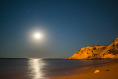 A serene coastal night illuminated by the full moon, casting a tranquil lunar glow over the calm sea and creating a majestic seaside beauty clipart