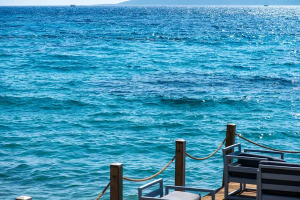 Güneşli gökyüzünün altında deniz kenarında rahat koltuklar ve koltuklar rahatlamak ve nefes kesici okyanus manzaralarının tadını çıkarmak için mükemmel bir yer sunuyor..