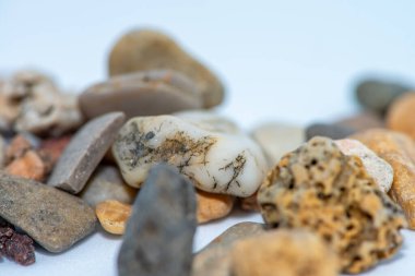 A close-up macro shot of smooth, colorful pebble stones arranged on a white background, showcasing their natural textures and intricate details. clipart