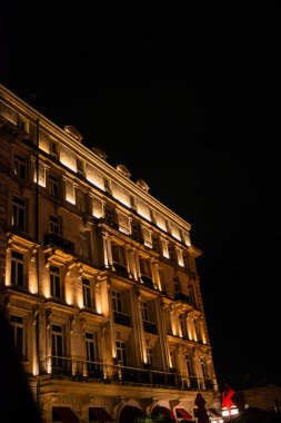 Bir otel binası gece şık bir şekilde parıldıyor, şık duvar yıkama ışıklarıyla aydınlatılıyor, modern mimari ve şehir manzarasında zarif bir tasarım sergiliyor..