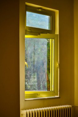 İçerideki sarı pencereden sıcak ve samimi bir manzara, güneş ışığının odayı canlı bir ışıltıyla yıkadığı, davetkar ve rahat bir atmosfer yarattığı yer..