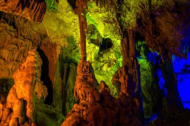 Journey through a vibrant cave adorned with colorful walls, stalactites, and stalagmites, revealing the underground beauty of nature's geological wonders. clipart