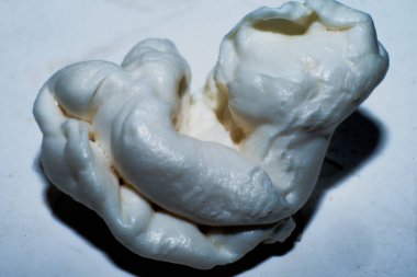 Çiğnenmiş bir sakızın dokusunu ve yapışkan yapısını temiz beyaz arka planda yakalayan detaylı bir makro fotoğraf..