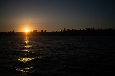 İstanbul Boğazı 'nın üzerinde çarpıcı bir günbatımı var. Gökyüzü turuncu ve pembe sıcacık renklerle parlıyor. Suyun ve şehrin üzerine güzel bir parıltı saçıyor..