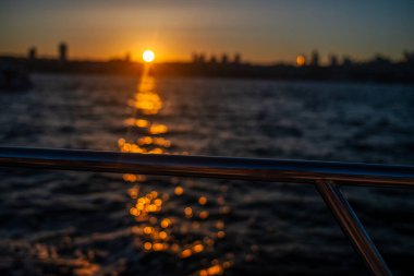 A stunning sunset over the Istanbul Bosphorus, with the sky ablaze in warm hues of orange and pink, casting a beautiful glow on the water and the cityscape. clipart