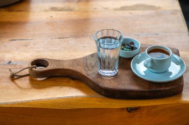 Çakıl taşlı çikolata ve bir bardak suyla Türk kahvesi sunumu, masada geleneksel ve zarif bir düzenleme sergileniyor.