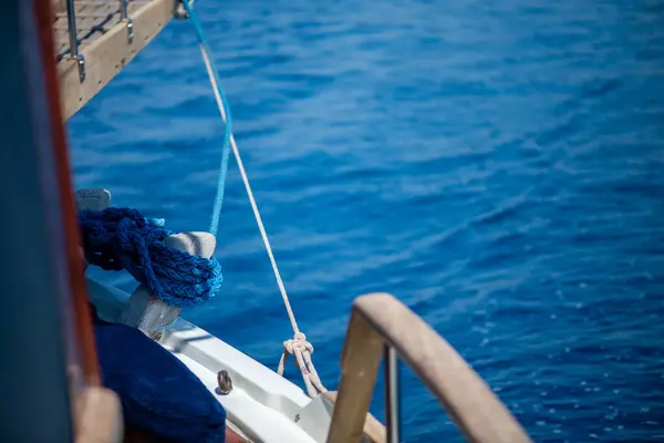 Sağlam bir çamurluk, kalın ipler ve denizde yüzen çeşitli deniz elementleri de dahil olmak üzere önemli gemi parçalarının detaylı bir görüntüsü, deniz yaşamının engebeli güzelliğini yakalıyor..