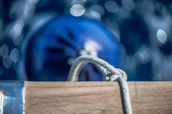 Sağlam bir çamurluk, kalın ipler ve denizde yüzen çeşitli deniz elementleri de dahil olmak üzere önemli gemi parçalarının detaylı bir görüntüsü, deniz yaşamının engebeli güzelliğini yakalıyor..