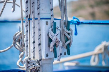 Geminin direğine sıkıca bağlanmış güçlü ve yıpranmış halatların yakın çekim görüntüsü denizcilik yelkenciliğinin işçiliğini ve temel donanımını vurguluyor..