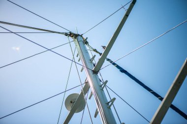 Geminin direğine sıkıca bağlanmış güçlü ve yıpranmış halatların yakın çekim görüntüsü denizcilik yelkenciliğinin işçiliğini ve temel donanımını vurguluyor..