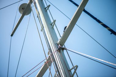 Geminin direğine sıkıca bağlanmış güçlü ve yıpranmış halatların yakın çekim görüntüsü denizcilik yelkenciliğinin işçiliğini ve temel donanımını vurguluyor..