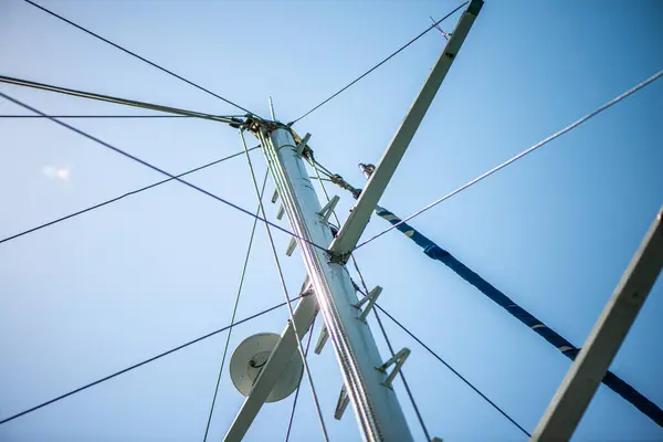 Geminin direğine sıkıca bağlanmış güçlü ve yıpranmış halatların yakın çekim görüntüsü denizcilik yelkenciliğinin işçiliğini ve temel donanımını vurguluyor..