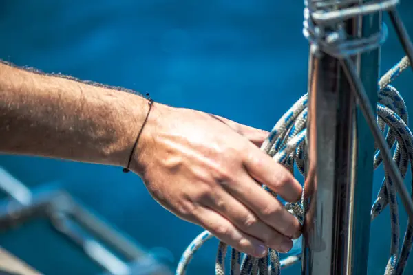 Yelkenli ipiyle güçlü bir düğüm atan, denizcilik zanaatkarlığı ve yelkencilik uzmanlığı sergileyen ellerin yakın çekimi..
