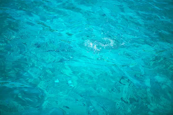 Derin mavi denizin çarpıcı bir görüntüsü, suların yüzeyindeki hafif dalgalanmaları ve güneş ışığının yansımalarını yakalıyor.