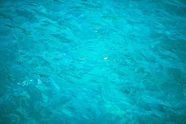 Derin mavi denizin çarpıcı bir görüntüsü, suların yüzeyindeki hafif dalgalanmaları ve güneş ışığının yansımalarını yakalıyor.