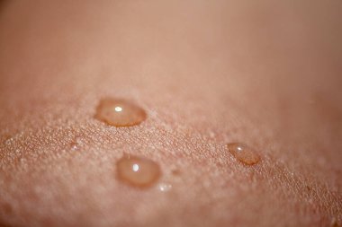 Oldukça detaylı bir makro çekim pürüzsüz cilt üzerinde parıldayan su damlacıkları yakalamak, dokuyu, tazeliği ve doğal güzelliği vurgulamak.