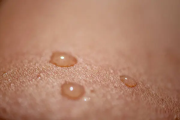 Oldukça detaylı bir makro çekim pürüzsüz cilt üzerinde parıldayan su damlacıkları yakalamak, dokuyu, tazeliği ve doğal güzelliği vurgulamak.