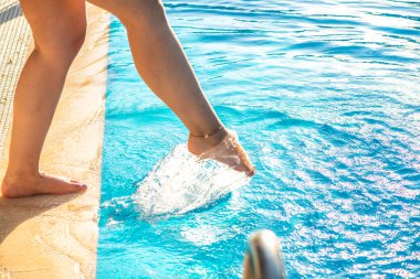 Bir kadının, batan güneşin sıcacık parıltısıyla aydınlanan bacağıyla havuz suyunu neşeyle sıçrattığı rüya gibi ve ferahlatıcı bir an..