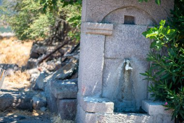 Taştan ya da kırsal malzemelerden yapılmış, tatlı suyla yavaşça akan, kırsal alanda sakin bir atmosfer yaratan pitoresk bir köy çeşmesi..