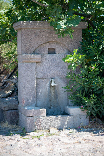 A picturesque village fountain, made from stone or rustic materials, gently flowing with fresh water, creating a serene atmosphere in a rural setting.