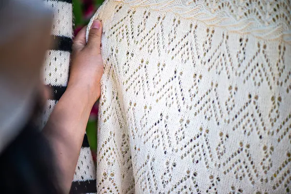 Bir kadının elinin nazikçe bir yün hatıra tutarken, yumuşaklığını ve el yapımı eşyanın karmaşık dokusunu gösteren bir yakın plan..