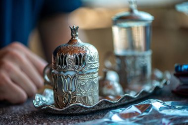 Geleneksel el yapımı Türk kahve fincanının, eski ve yıpranmış taş bir yüzeye yerleştirilmiş, detaylı ve atmosferik bir görüntüsü..