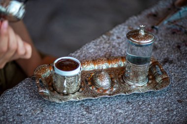 Geleneksel el yapımı Türk kahve fincanının, eski ve yıpranmış taş bir yüzeye yerleştirilmiş, detaylı ve atmosferik bir görüntüsü..