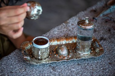 Geleneksel el yapımı Türk kahve fincanının, eski ve yıpranmış taş bir yüzeye yerleştirilmiş, detaylı ve atmosferik bir görüntüsü..