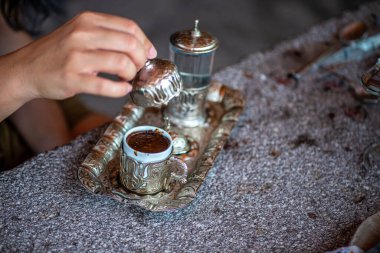 Geleneksel el yapımı Türk kahve fincanının, eski ve yıpranmış taş bir yüzeye yerleştirilmiş, detaylı ve atmosferik bir görüntüsü..