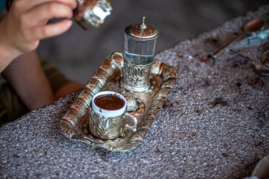 Geleneksel el yapımı Türk kahve fincanının, eski ve yıpranmış taş bir yüzeye yerleştirilmiş, detaylı ve atmosferik bir görüntüsü..