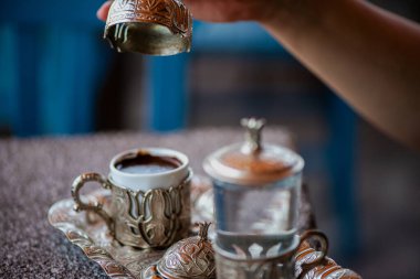 Geleneksel el yapımı Türk kahve fincanının, eski ve yıpranmış taş bir yüzeye yerleştirilmiş, detaylı ve atmosferik bir görüntüsü..