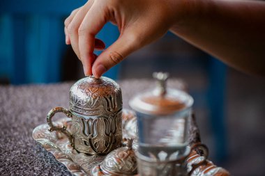 Geleneksel el yapımı Türk kahve fincanının, eski ve yıpranmış taş bir yüzeye yerleştirilmiş, detaylı ve atmosferik bir görüntüsü..