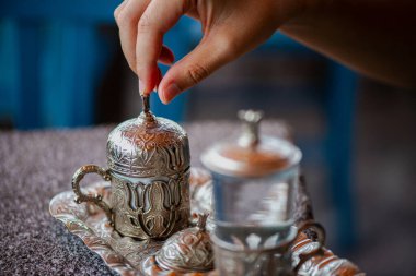 Geleneksel el yapımı Türk kahve fincanının, eski ve yıpranmış taş bir yüzeye yerleştirilmiş, detaylı ve atmosferik bir görüntüsü..