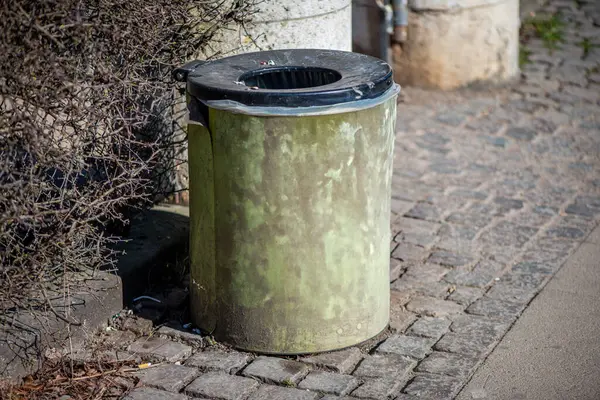 Şehir sokağının kenarına konmuş standart bir çöp kutusunun olduğu gerçekçi bir sokak sahnesi..