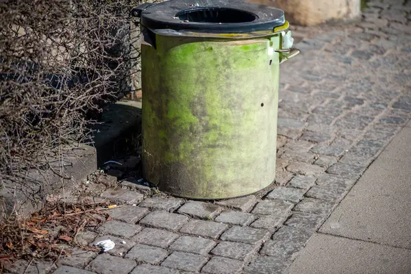 Şehir sokağının kenarına konmuş standart bir çöp kutusunun olduğu gerçekçi bir sokak sahnesi..