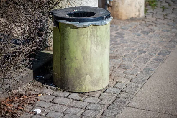 Şehir sokağının kenarına konmuş standart bir çöp kutusunun olduğu gerçekçi bir sokak sahnesi..