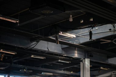 Modern bir mimari ortamda, doğrudan ham beton tavana kurulmuş elektronik bir sistemin kablolarının ve bağlantılarının detaylı bir görüntüsü..