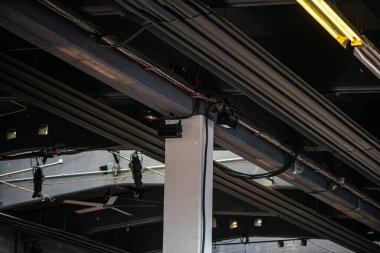 Modern bir mimari ortamda, doğrudan ham beton tavana kurulmuş elektronik bir sistemin kablolarının ve bağlantılarının detaylı bir görüntüsü..