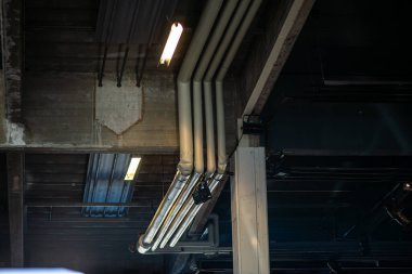 Modern bir mimari ortamda, doğrudan ham beton tavana kurulmuş elektronik bir sistemin kablolarının ve bağlantılarının detaylı bir görüntüsü..