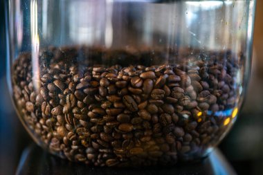 Kahve çekirdeklerinin yakın plan görüntüsü ticari düzeyde bir kızartma makinesinde kızartılıyor, zengin dokuları, renkleri ve kahve kızartma işleminin ısısını gösteriyor..