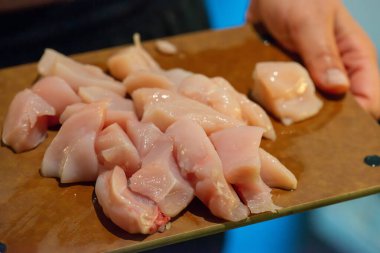 Yakın çekim, yüksek detay makro çekim. Bir kadın tavuk sotesi hazırlarken, cızırtılı malzemeler sergilerken ve sıcak bir mutfak ortamında yemek pişirirken görülüyor.